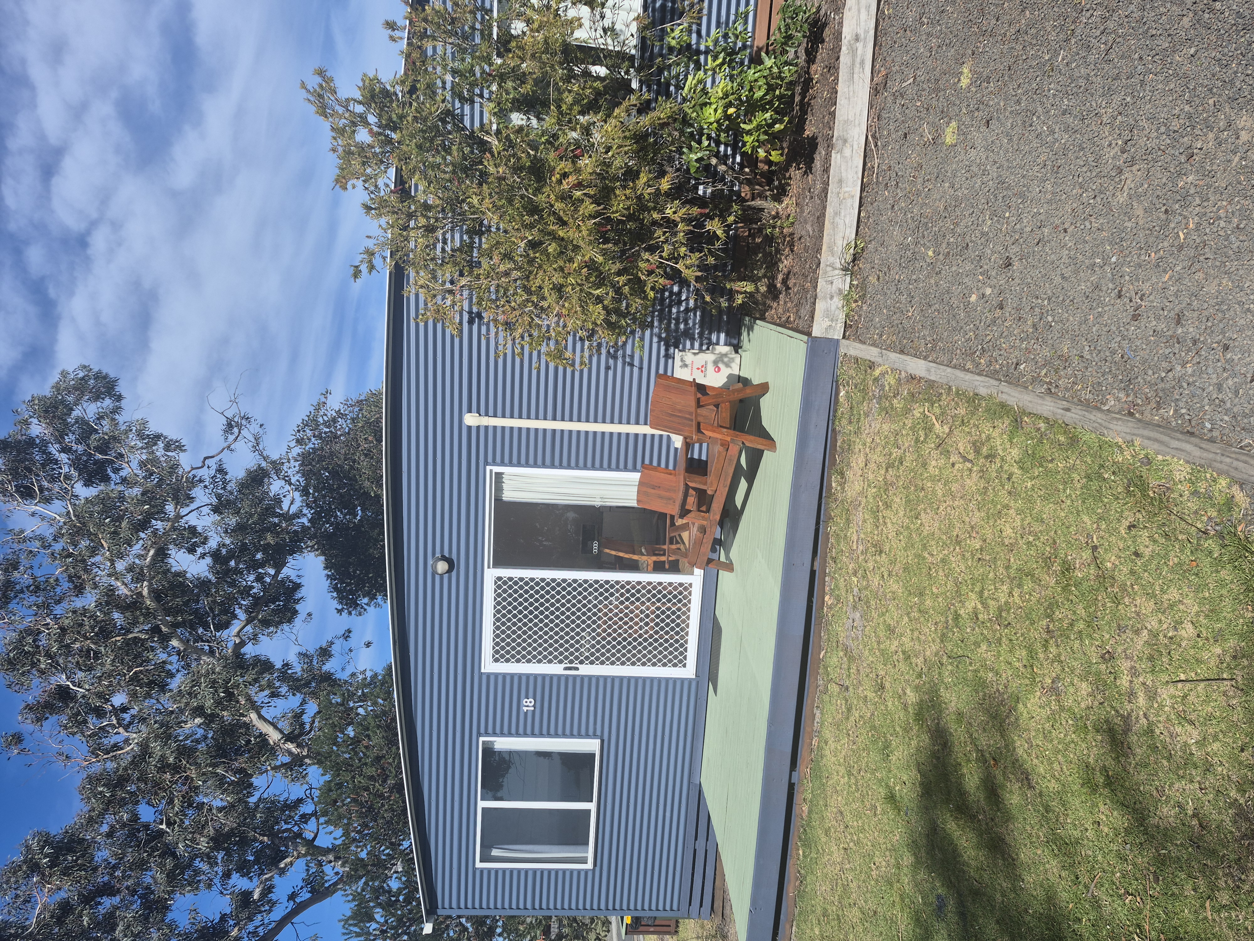 Blue deluxe cabin with timber outdoor chairs on the deck